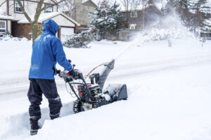 Snow removal technician cleaning sidewalk with equipment